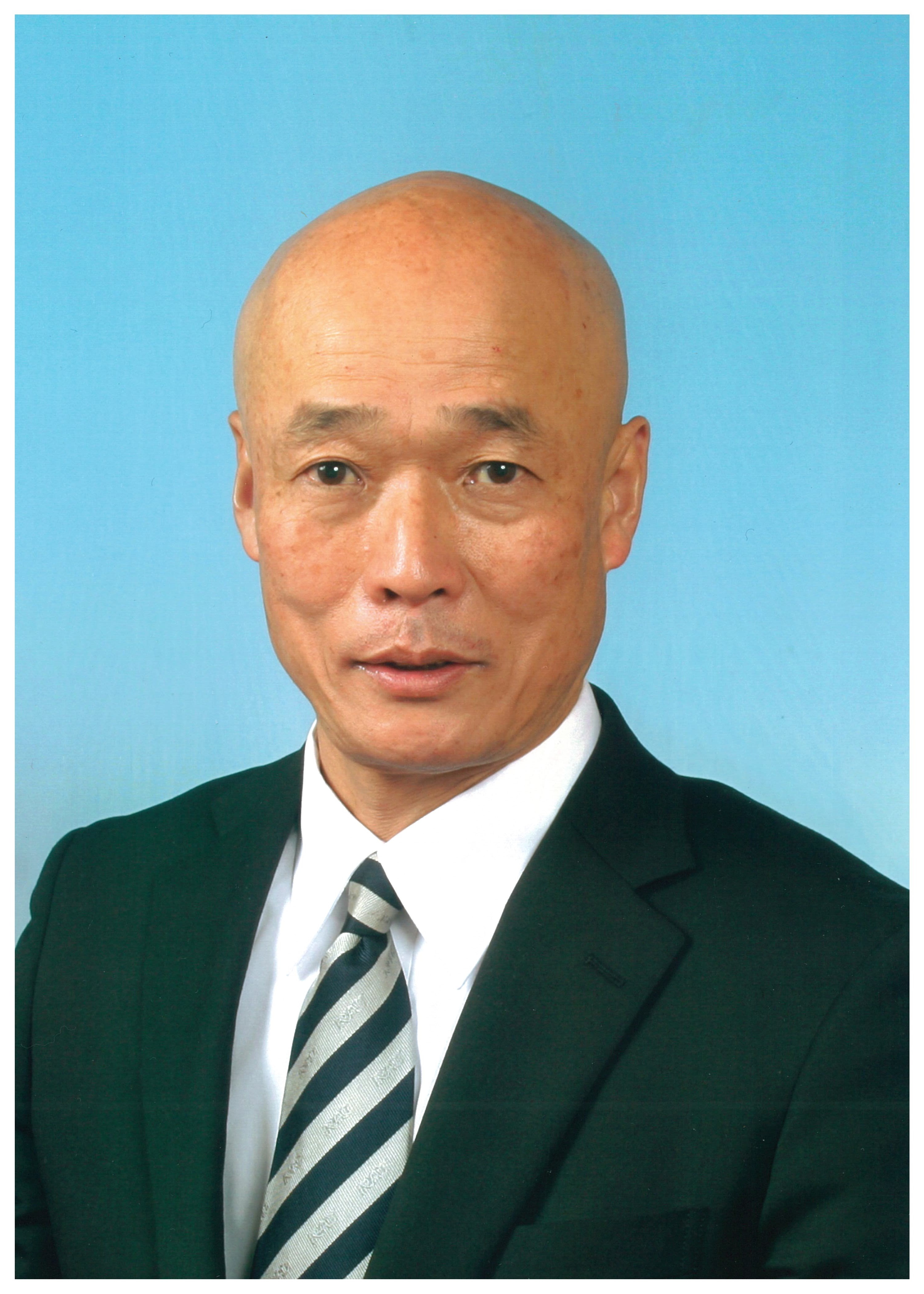 ビジネススーツを着た町長の肖像写真で、背景は青色です。