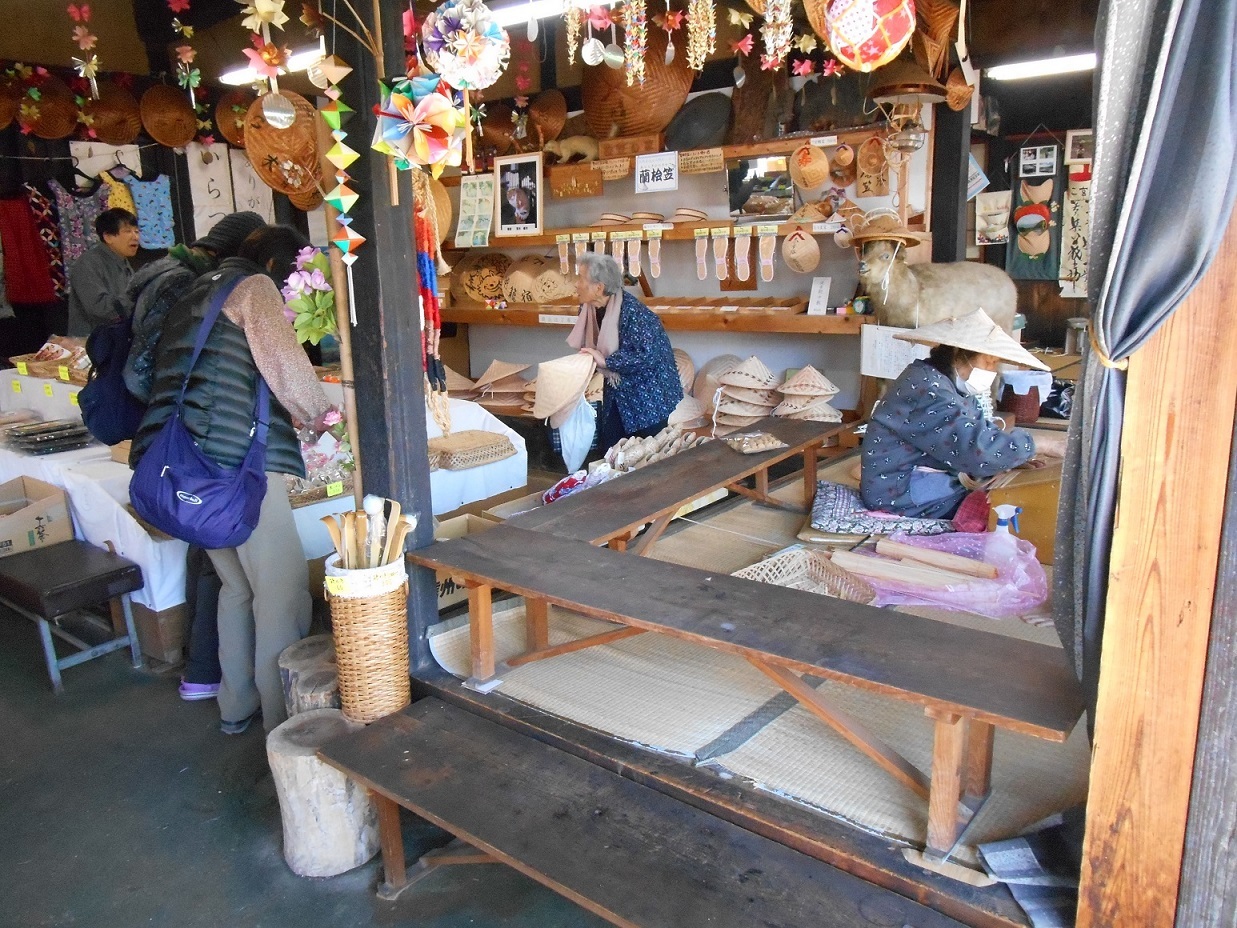 屋内の市場風の店で複数の人が座って食事や会話を楽しむ長い木製のカウンターや飾りが並ぶ光景