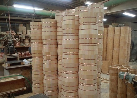 作業場に積み上げられた同じ形状の丸い木製の桶や樽が列を成して並び周囲に木材や道具が見える