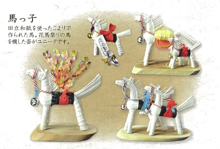 白い土人形の馬のミニチュアが四つ緑の台座に載り赤い鞍や花飾りがあり左上に日本語の説明文がある写真