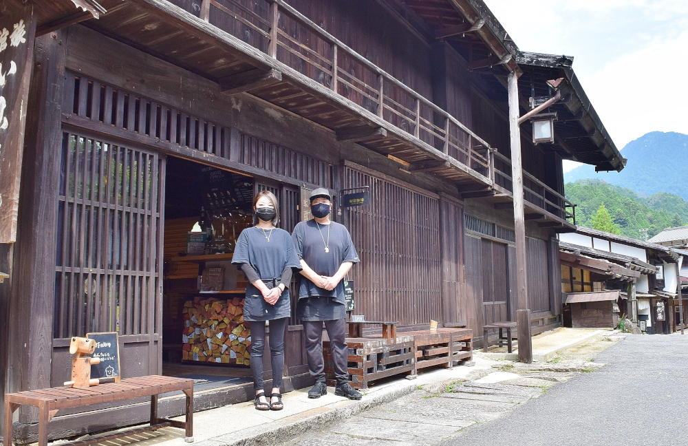 古い木造の商家の前に店員が並んで立つ