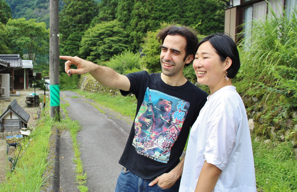 緑に囲まれた田舎道で二人並んで立っている