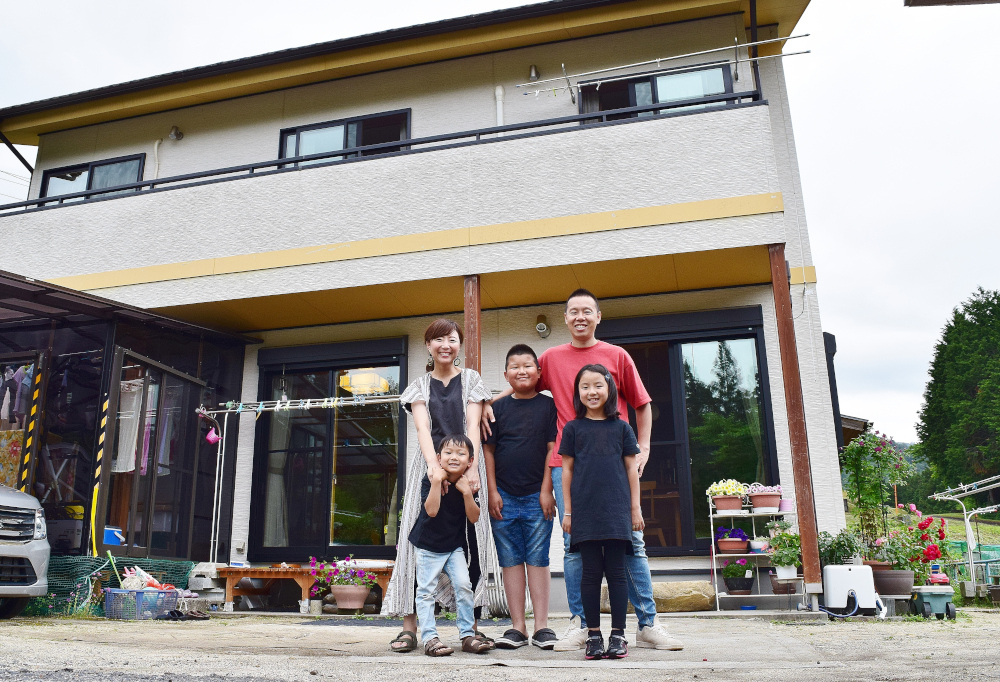 二階建ての家の前に並んで立つ一家