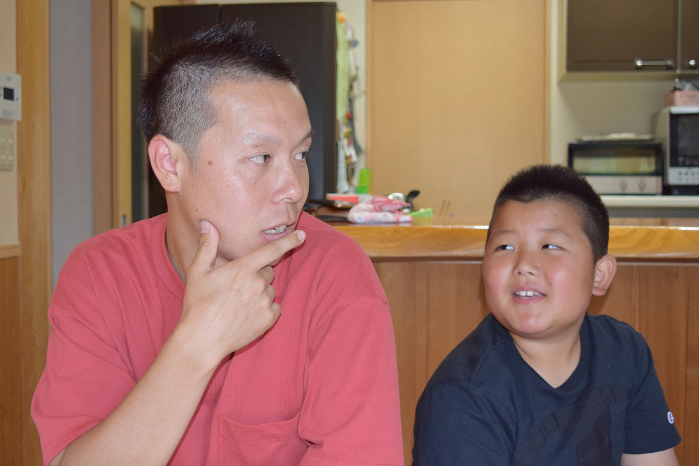 室内のテーブル前に座る大人と子どもが並んでいる写真