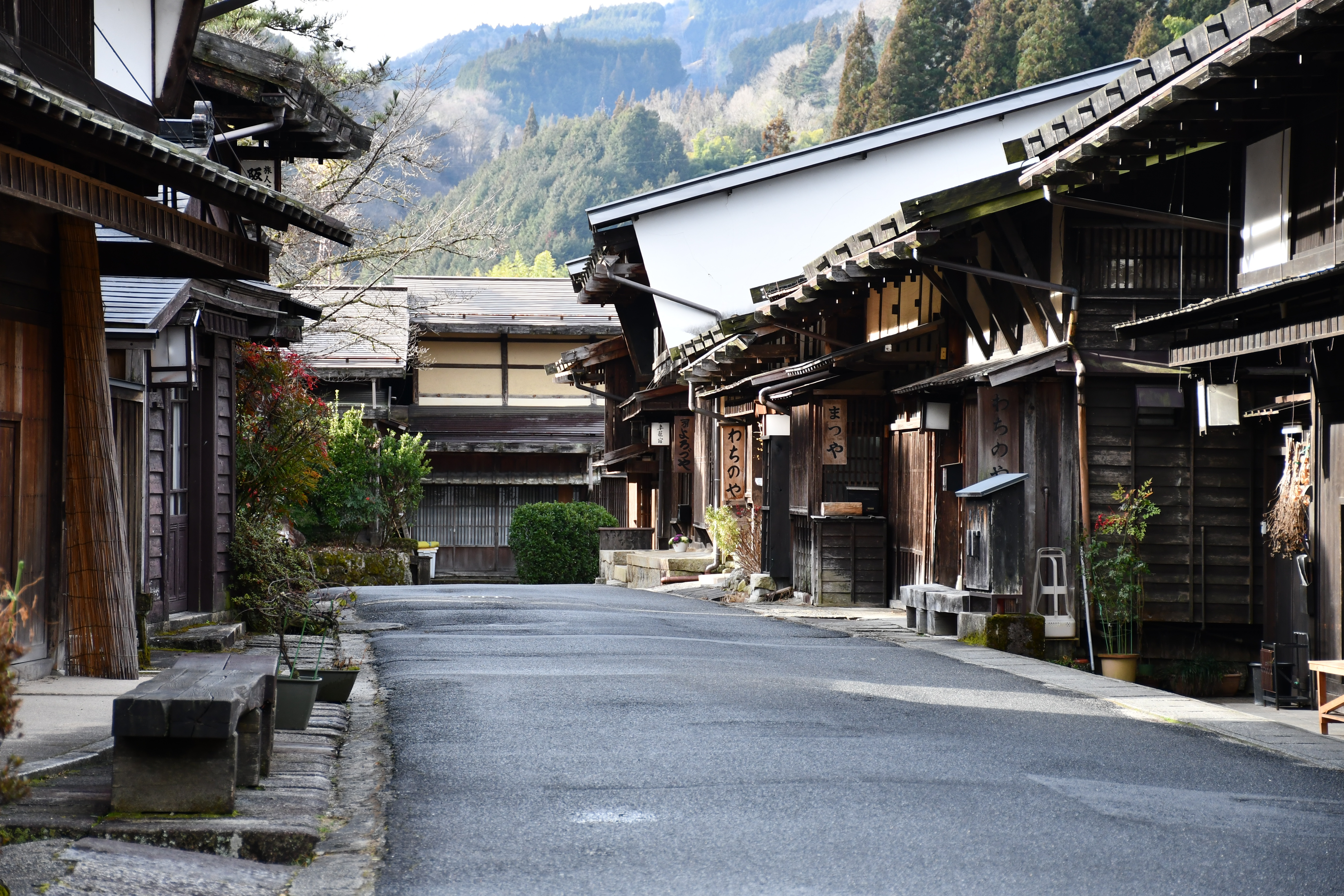 古い木造の町家が並ぶ静かな山里の通りと遠くに見える山々